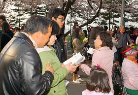 '来观赏春花的游客们，接过传单在认真阅读'